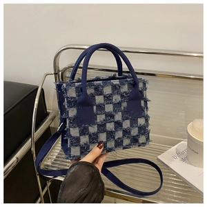 Detail einer blau-weißen karierten Denim-Tote-Bag mit Fransen und doppelten Riemen