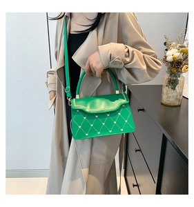 Detail of green quilted mini bag featuring heart embroidery and wavy chain flap edge