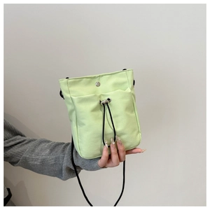 Detail of light green canvas mini crossbody bag with drawstring pocket and snap closure