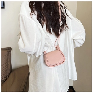 Vista posteriore di una mini borsa a sella rosa indossata su una camicia bianca pulita
