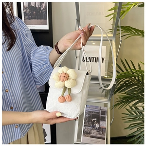 Détail du sac bandoulière en tissu blanc avec fleur jaune en peluche et lanière en cuir