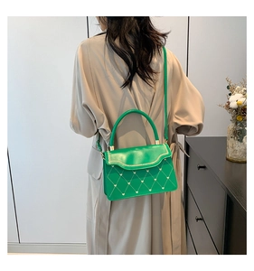Detail of green leather crossbody bag with heart quilting and chain metal accents