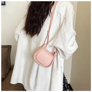 Dettaglio mini borsa a sella rosa in ecopelle con texture e vestibilità a tracolla su modella