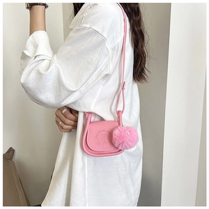 Détail du mini sac selle rose avec lettres embossées et charm de balle en peluche