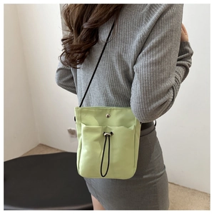 Detail van avocado groene nylon crossbodytas met trekkoordzakje op een model