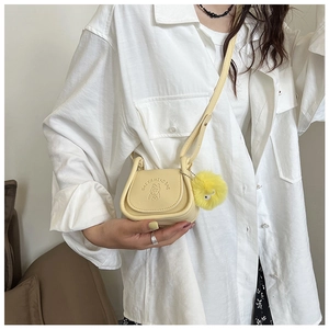 Détail du sac selle en cuir PU jaune avec gaufrage cartoon et breloque pompon doux