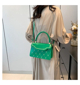 Detail view of bright green quilted crossbody bag with heart patterns on a female model