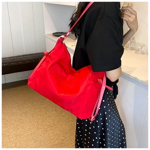 Detail of red hobo bag showing high-gloss nylon fabric and exquisite tone-on-tone embroidery