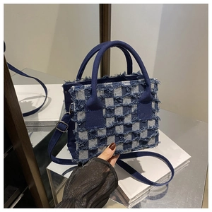 Detailaufnahme der karierten Denim-Handtasche mit ausgefransten Kanten und Schultergurt