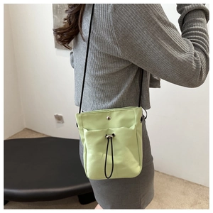 Detail van de lichtgroene nylon crossbodytas met trekkoordzakje en metalen drukknoopsluiting