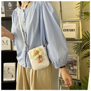 Détail d'un mini sac bandoulière blanc avec une fleur 3D jaune et une fermeture à rabat
