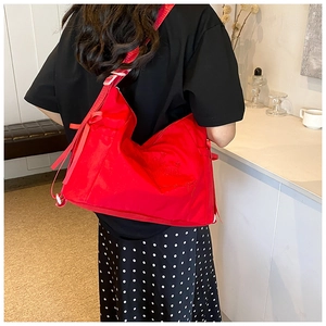 Detail view of large red nylon bag featuring elegant letter embroidery and side webbing