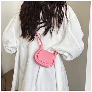 Dettaglio della mini borsa a tracolla rosa a sella indossata lateralmente da una modella