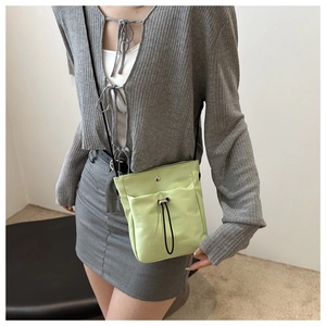 Detail van de lichtgroene crossbodytas met trekkoord op een casual outfit