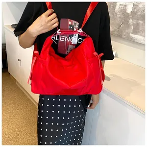 Detail of red nylon tote bag featuring side drawstring bows and elegant embroidery