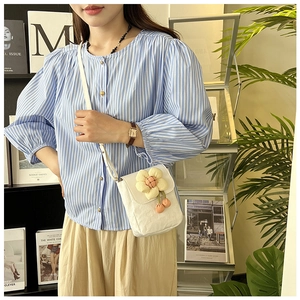 Détail d'un petit sac bandoulière en toile blanche avec décoration de fleur jaune