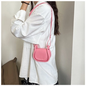 Dettaglio di una mini borsa a tracolla rosa in pelle PU con patta curva e tracolla fine