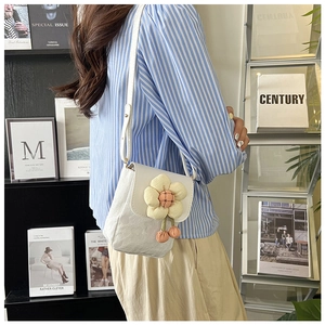 Gros plan du sac à bandoulière en dentelle blanche avec marguerite 3D et pompons roses