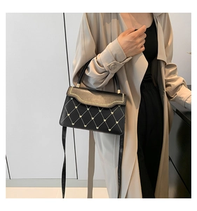 Detail of vintage black leather crossbody bag with gold heart patterns and quilted texture