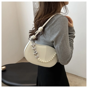 Detail of white semi-circle saddle bag with glossy finish and decorative pearl chain