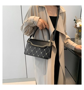 Detail of black quilted shoulder bag with gold heart studs and chic zip trim decoration