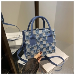 Detail der blau-weiß karierten Handtasche mit Fransen und Denim-Struktur