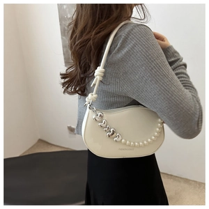 Détail du sac croissant blanc avec chaîne cœur et perles porté par le modèle