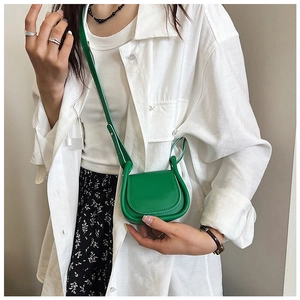 Mini borsa a tracolla verde con design a U e patta, indossata da una modella in stile casual
