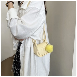 Détail d'un mini sac selle crème avec motif ours en relief et pompon jaune en peluche