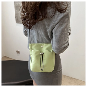 Detailed view of mint green canvas phone bag with drawstring pocket and metal snap button