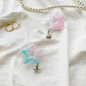 Close-up of glitter heart and star phone grips with charms on white fabric