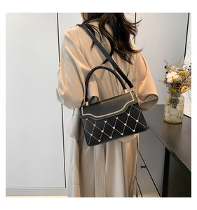 Model view of black leather handbag with golden heart embroidery and chain detail