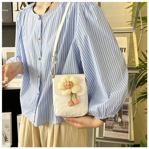Gros plan du sac bandoulière blanc avec breloque tournesol et texture jacquard