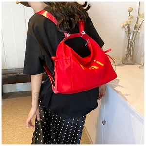 Detail view of red nylon backpack with yellow printed letters and side drawstrings