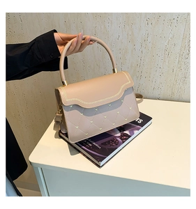 Detail of minimalist leather crossbody bag with heart quilting and wavy flap design