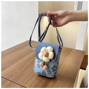 Gros plan du petit sac bandoulière avec tissu floral bleu et fleur 3D blanche décorative