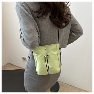 Close-up of light green minimalist canvas crossbody bag shown on a model for scale