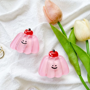 Pink jelly cherry phone grip holder with cute smiley face on textured fabric background