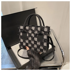 Detail der karierten Handtasche mit ausgefransten Denim-Kanten auf Deko-Requisiten