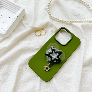 Detail of green star phone grip and metallic charm on a modern smartphone case