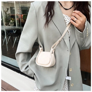 Borsa a sella bianco crema abbinata a blazer grigio e abito a pois per un look elegante