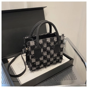Detail der karierten Handtasche mit Fransenbesatz in einer Luxus-Geschenkbox