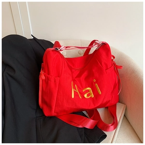 Detail of red nylon tote bag with yellow Hai embroidery and side ribbon bow decoration