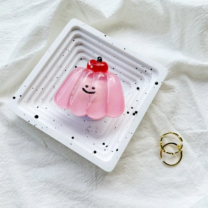 Close-up of pink jelly phone grip with cherry decor and smile face on a white tray