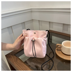 Detailed shot of a pink nylon drawstring mini crossbody bag on a cafe table setting