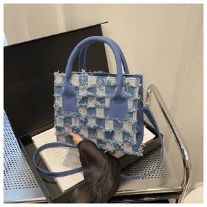 Details der blau karierten Handtasche mit Fransenkanten und Trageoptionen