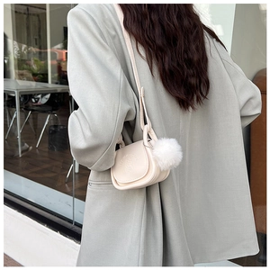 Détail du sac selle vintage crème avec gaufrage porté par un mannequin en veste grise