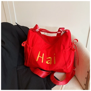 Detailed macro view of a large red tote bag with gold lettering and a side ribbon knot