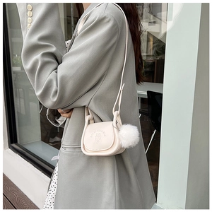 Mini sac selle crème avec motif lapin gaufré et pompon sur une veste verte