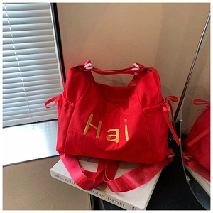 Detail of red canvas bag with yellow 'Hai' print, side drawstrings and zipper closure